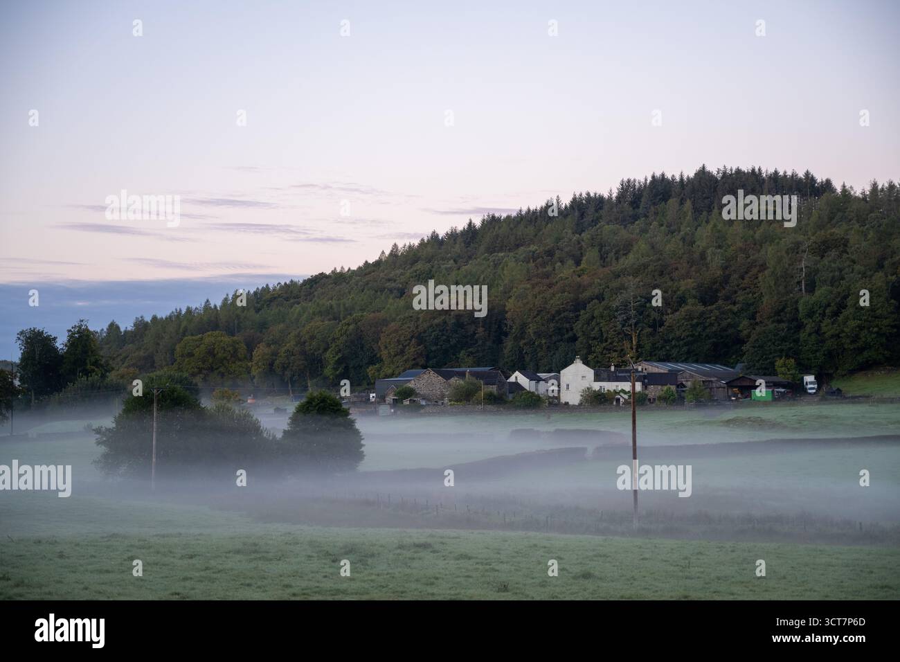 Mattina nebbiosa su terreni agricoli e cottage in Cumbria, con colline ondulate e boschi all'alba. Foto Stock