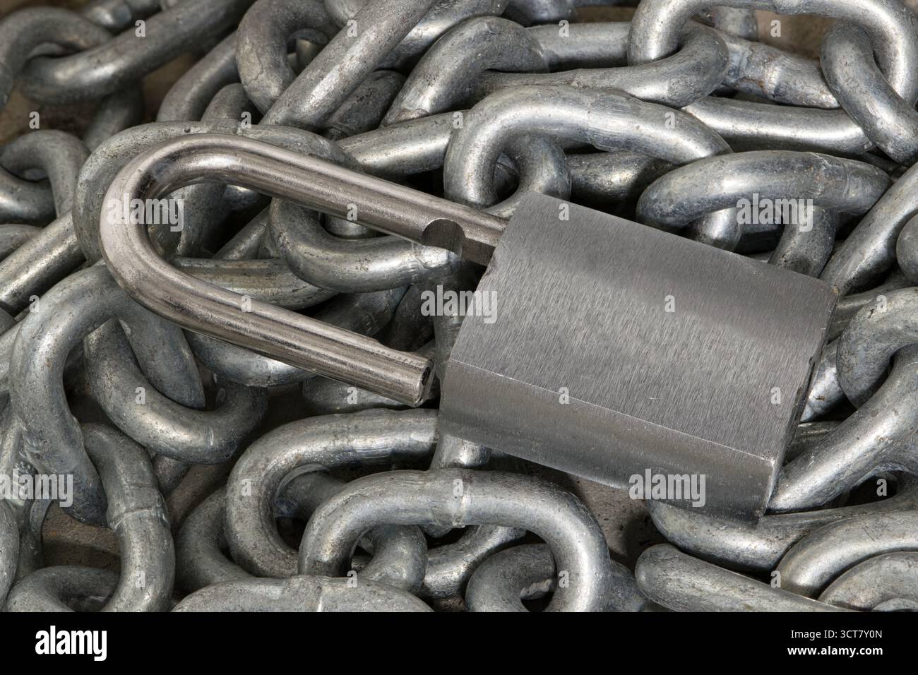 Lucchetto color argento sbloccato su un mucchio di catene concetto di sicurezza industriale STILL Life. Foto Stock