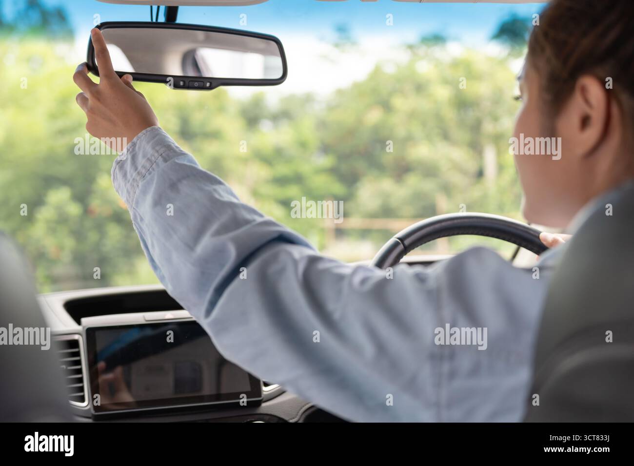 donna regola lo specchietto retrovisore dell'auto prima della guida, guida con intento, guida sicura, pratica di guida, donna allegra seduto comodamente sul sedile del conducente wi Foto Stock