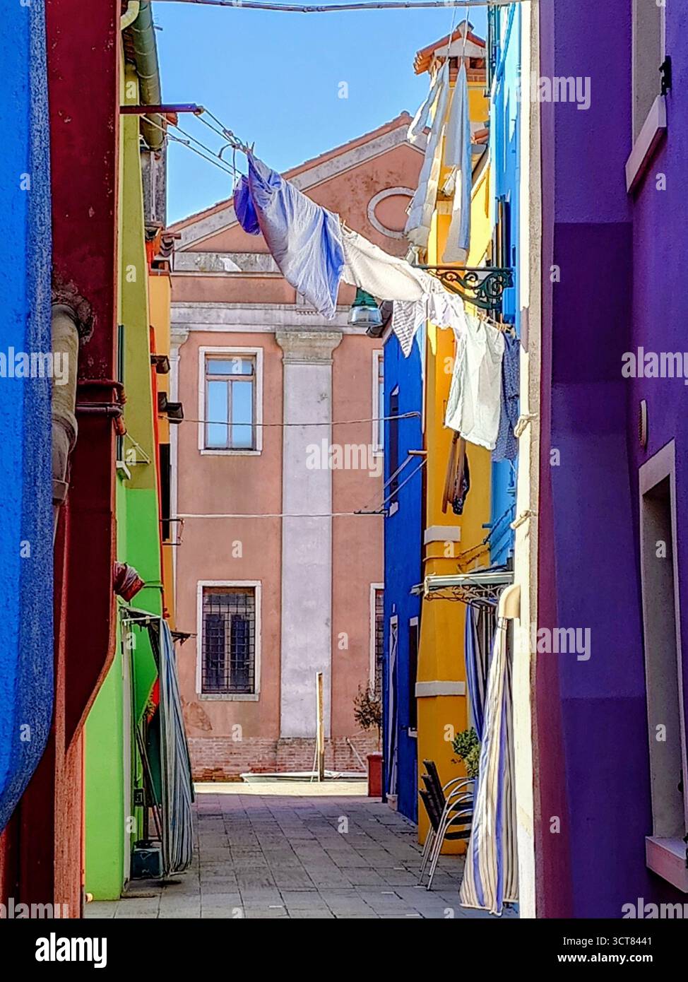Una via smalltalk con case colorate a Burano, Italia. Il lavaggio pende Adresse per la strada Foto Stock