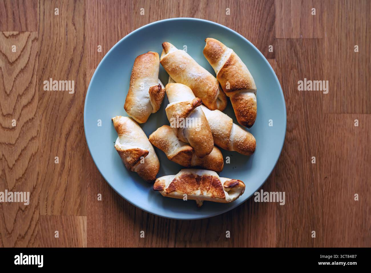 Rotoli di kipferl marrone dorato sul piatto, prodotti da forno rustici fatti in casa. Vista dall'alto. Foto Stock