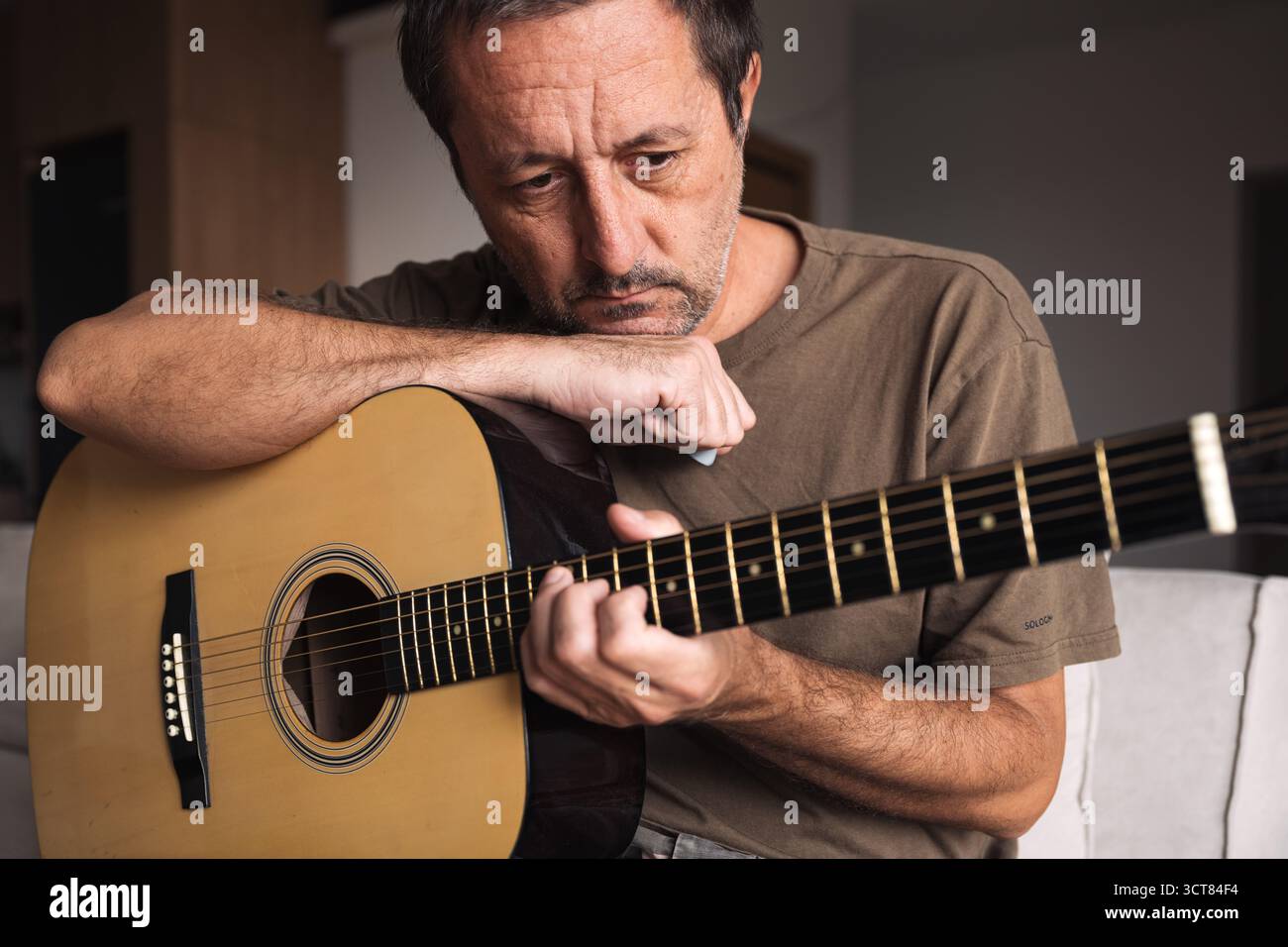 Musicista stanco che si appoggia alla chitarra, esprimendo frustrazione, stanchezza e burnout creativo. Messa a fuoco selettiva. Foto Stock