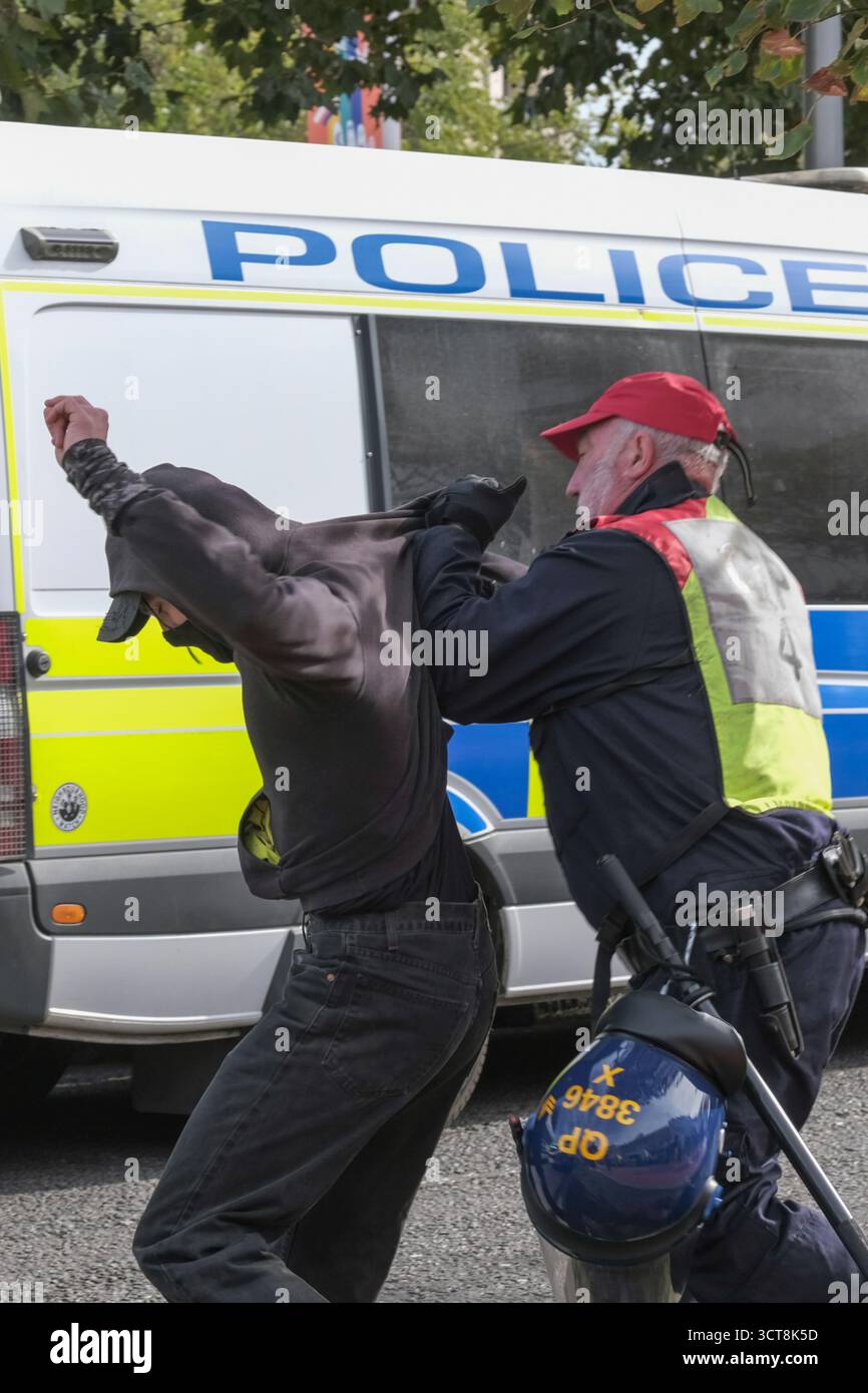 Bristol, Regno Unito. 5 ottobre 2025. Un manifestante antifascista viene allontanato dai patrioti. I patrioti di destra con le bandiere di San Giorgio e dell'Unione si riuniscono al Cenotafio di Bristol, per protestare contro l'immigrazione. Gli attivisti, molti che si identificano come antifascisti, che credono che migranti e rifugiati debbano essere accolti, hanno organizzato una contro-protesta. Avon e la polizia di Somerset hanno adottato misure per consentire una protesta pacifica, ma intendono tenere tutti al sicuro tenendo separate le due parti. Crediti: JMF News/Alamy Live News Foto Stock