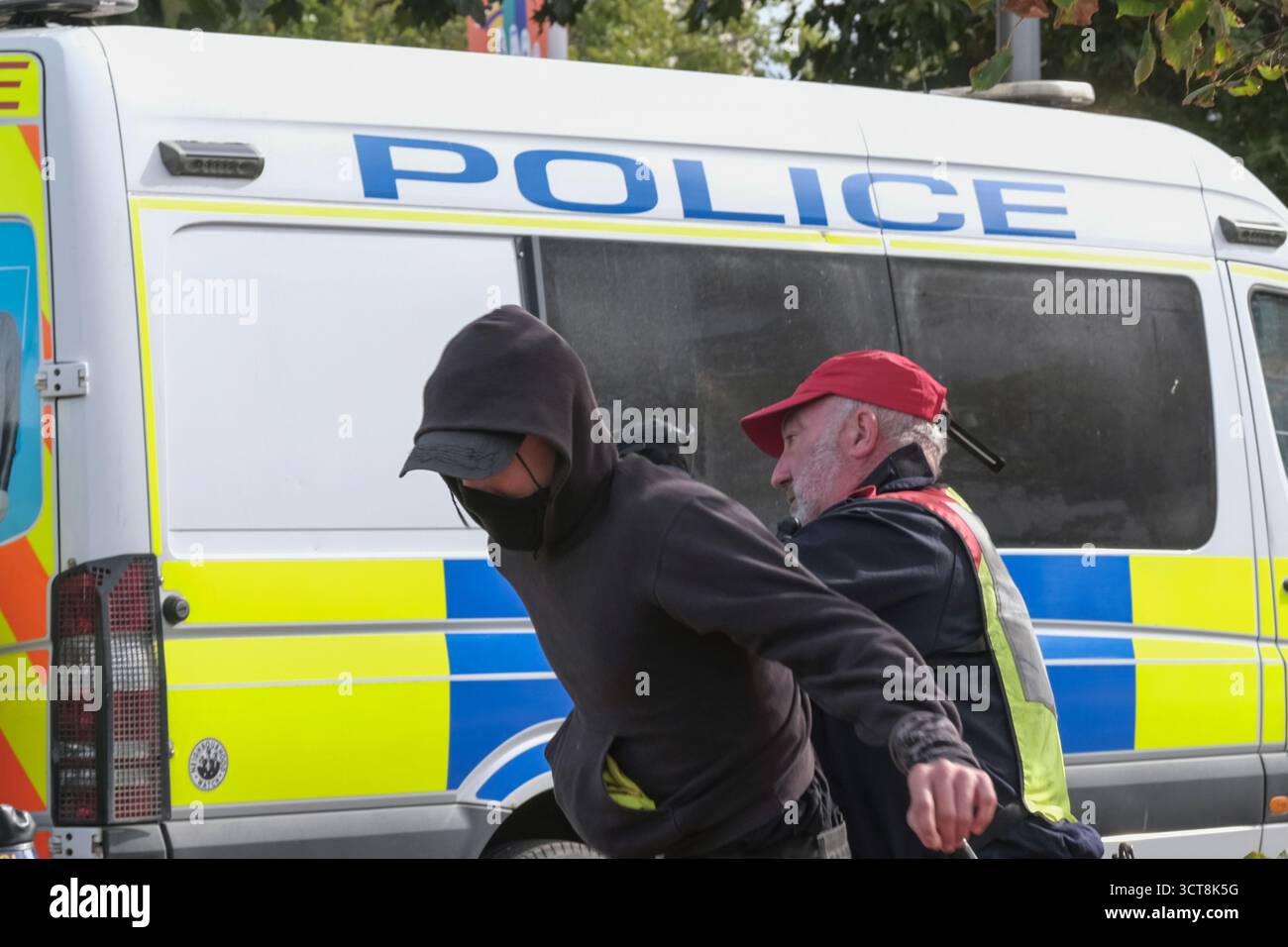 Bristol, Regno Unito. 5 ottobre 2025. Un manifestante antifascista viene allontanato dai patrioti. I patrioti di destra con le bandiere di San Giorgio e dell'Unione si riuniscono al Cenotafio di Bristol, per protestare contro l'immigrazione. Gli attivisti, molti che si identificano come antifascisti, che credono che migranti e rifugiati debbano essere accolti, hanno organizzato una contro-protesta. Avon e la polizia di Somerset hanno adottato misure per consentire una protesta pacifica, ma intendono tenere tutti al sicuro tenendo separate le due parti. Crediti: JMF News/Alamy Live News Foto Stock
