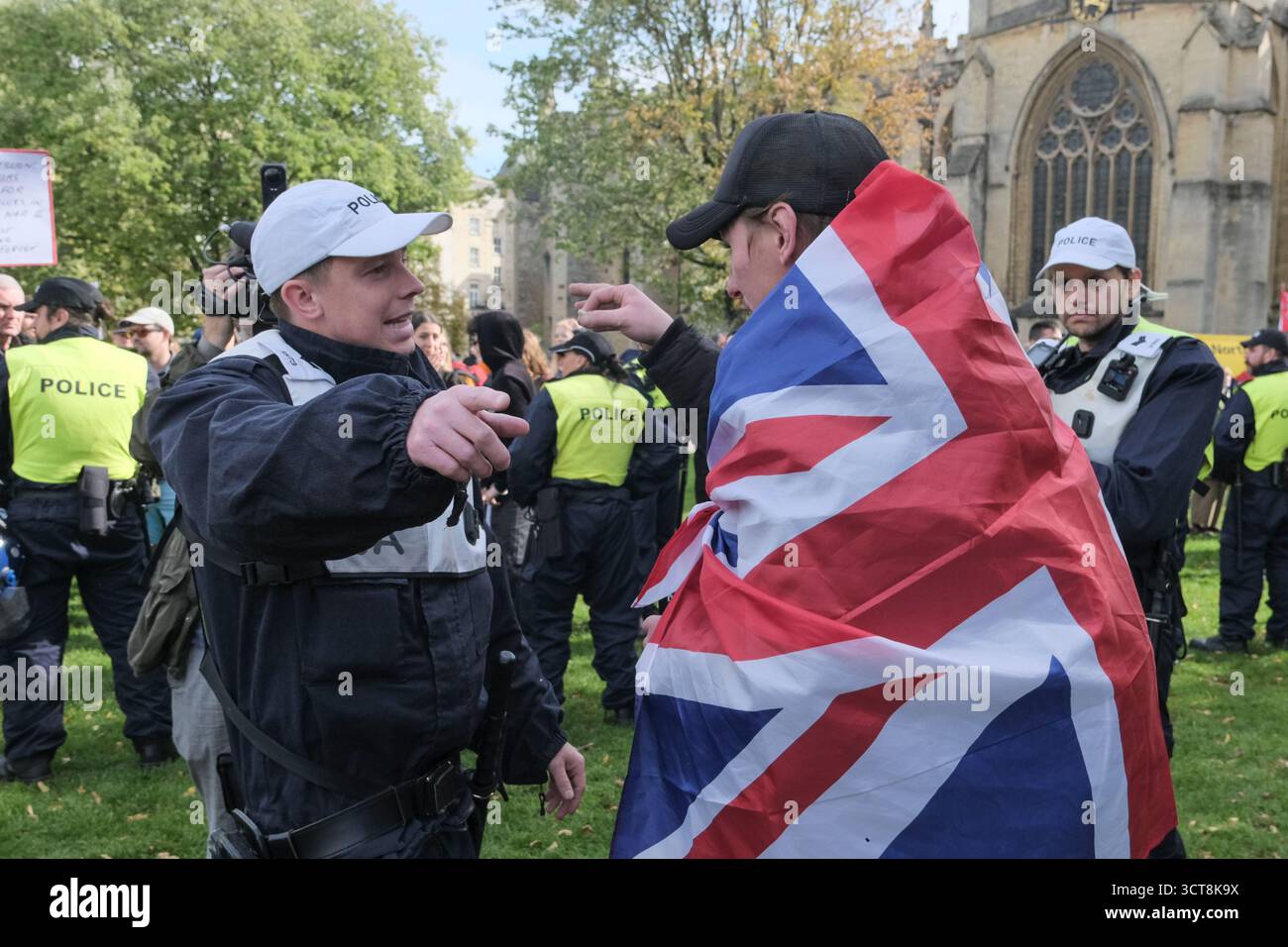 Bristol, Regno Unito. 5 ottobre. Un manifestante che si è trovato nella zona sbagliata riceve indicazioni dalla polizia. I cosiddetti patrioti, con San Giorgio e le bandiere dell'Unione si riuniscono al Cenotafio di Bristol, per protestare contro l'immigrazione. Gli attivisti, molti che si identificano come antifascisti, che credono che migranti e rifugiati debbano essere accolti, hanno organizzato una contro-protesta. Avon e la polizia di Somerset hanno adottato misure per consentire una protesta pacifica, ma intendono tenere tutti al sicuro tenendo separate le due parti. Crediti: JMF News/Alamy Live News Foto Stock