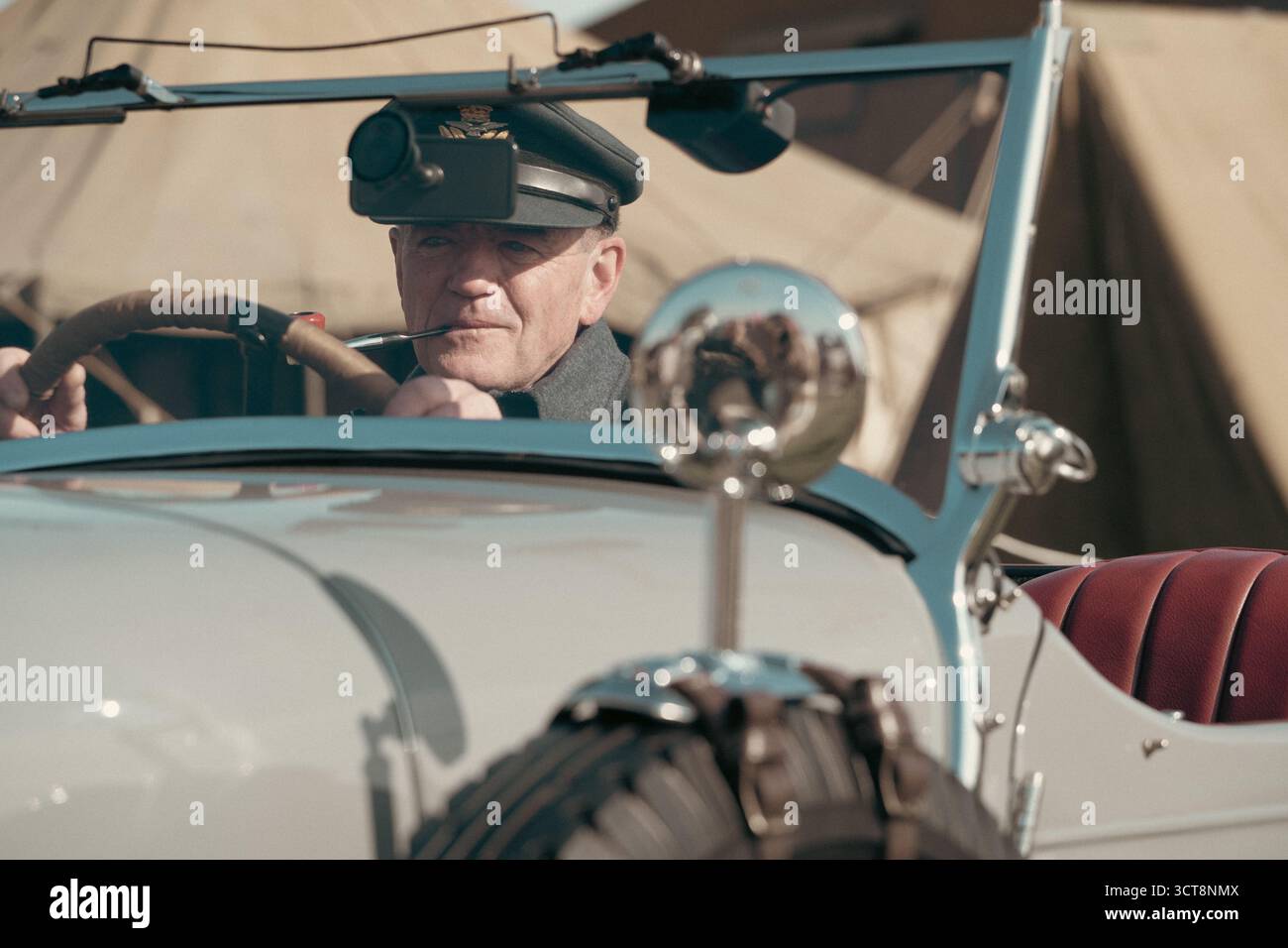 Autista militare d'epoca in uniforme d'epoca che guida un'auto classica aperta Foto Stock