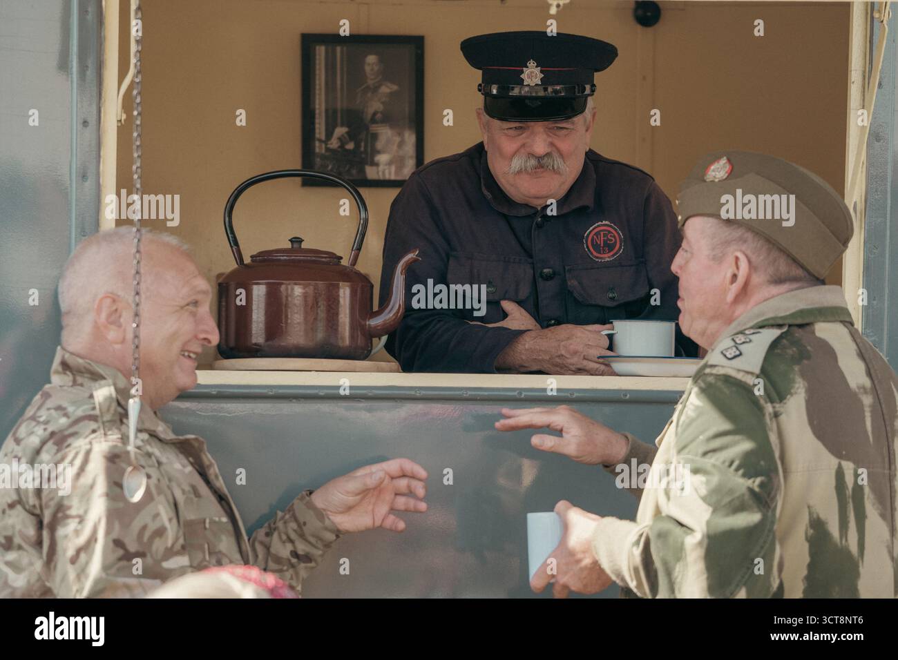 Veterani militari che si godono il tè e la conversazione in carrozza ferroviaria d'epoca durante l'evento Heritage Foto Stock