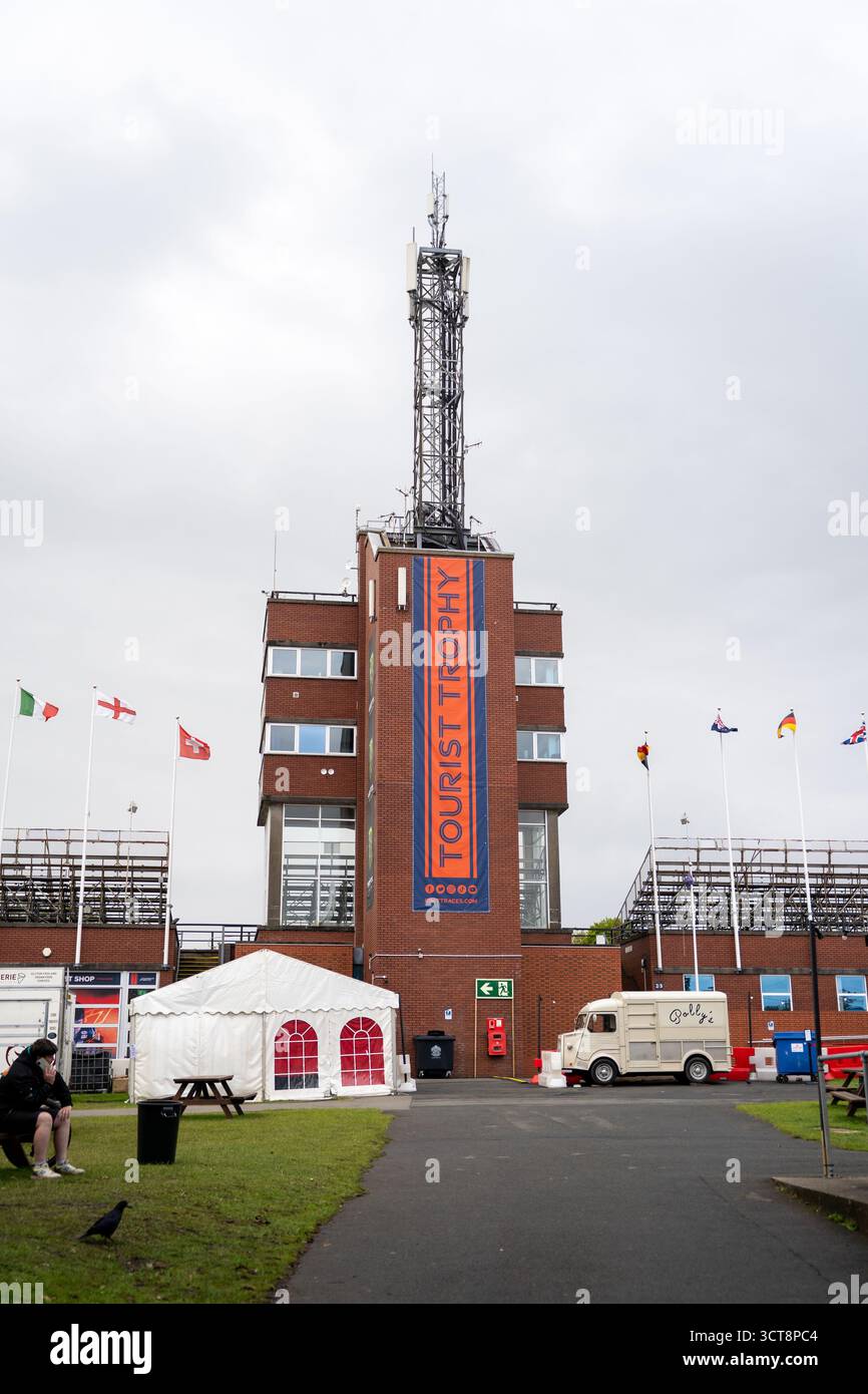 Edificio del Trofeo Turistico con albero delle comunicazioni e bandiere internazionali al campo TT dell'Isola di Man Foto Stock
