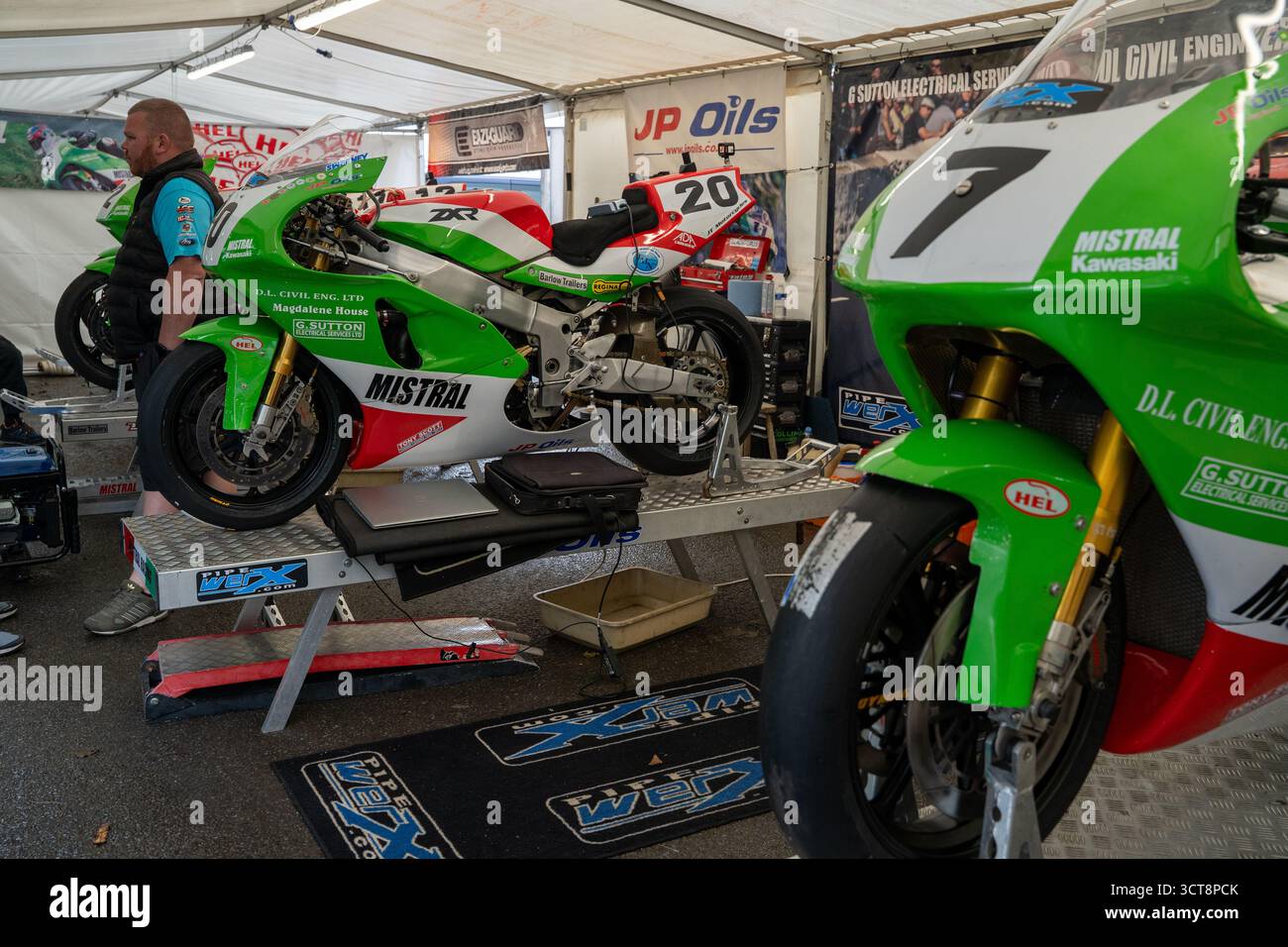Motociclette da corsa nel garage paddock con meccanico che prepara le moto per la competizione Foto Stock