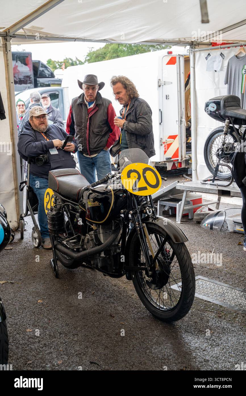 Motocicletta Vintage Velocette numero 20 nel paddock da corsa con meccanici e appassionati Foto Stock