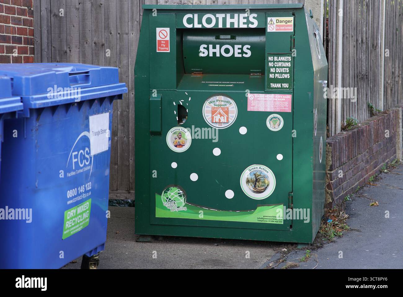 Contenitore per il riciclaggio di vestiti e scarpe verde accanto a un contenitore per il riciclaggio blu in una strada del Regno Unito, promuovendo il riutilizzo e la sostenibilità.Dorking, Inghilterra Foto Stock