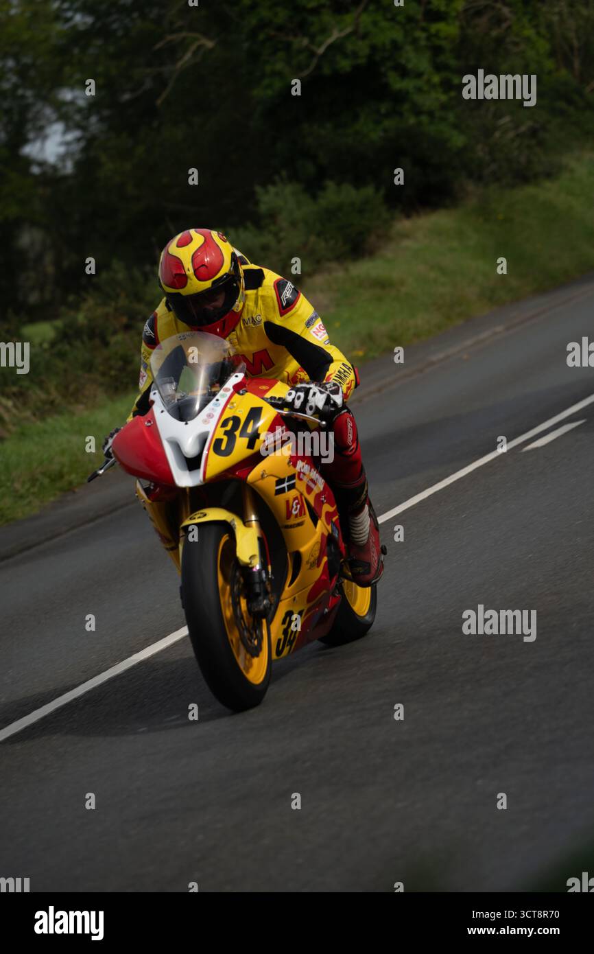 Motociclista da corsa in pelle gialla in curva sul campo TT dell'Isola di Man Foto Stock