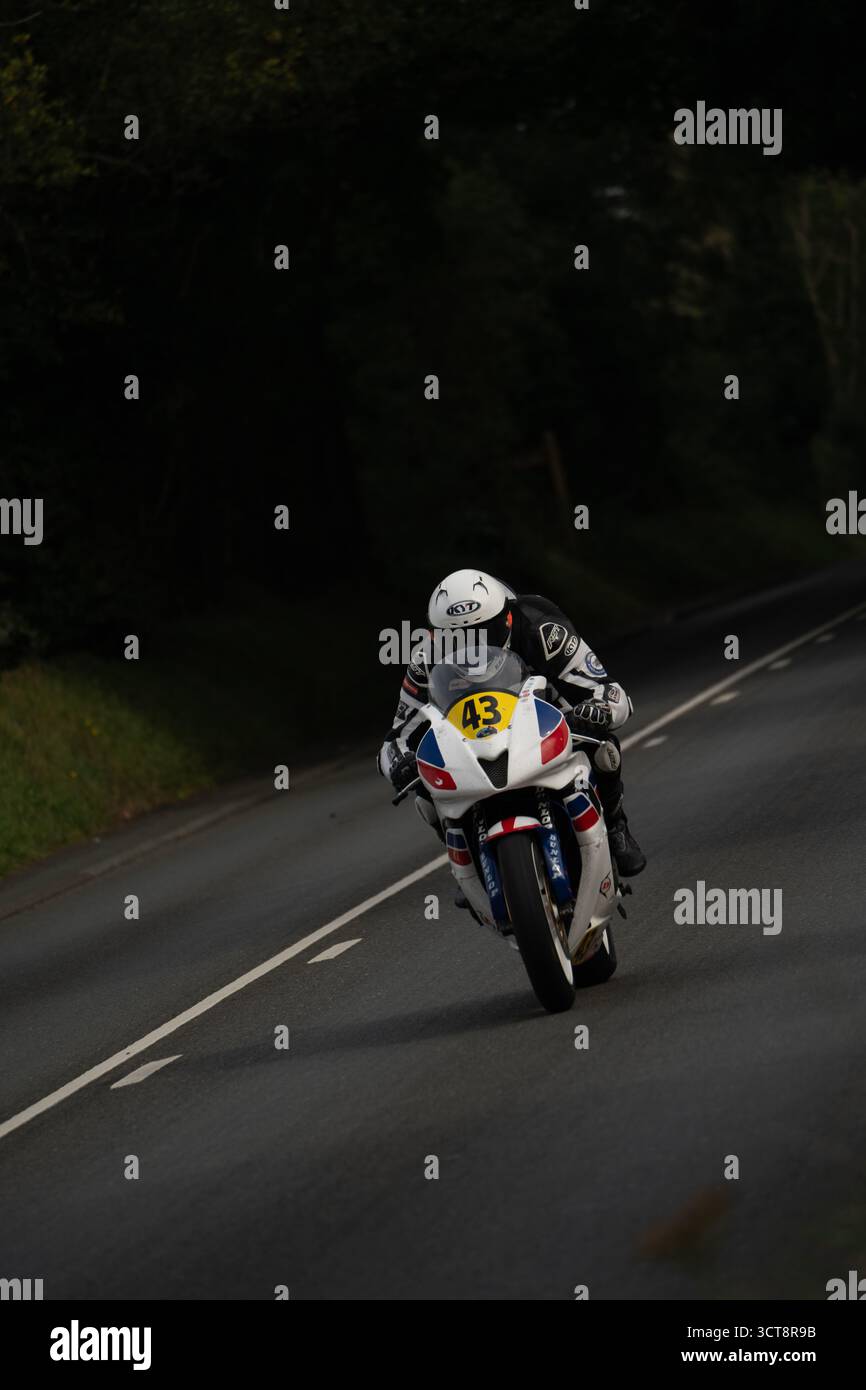 Il motociclista numero 43 gareggia sul campo TT dell'Isola di Man attraverso la campagna Foto Stock