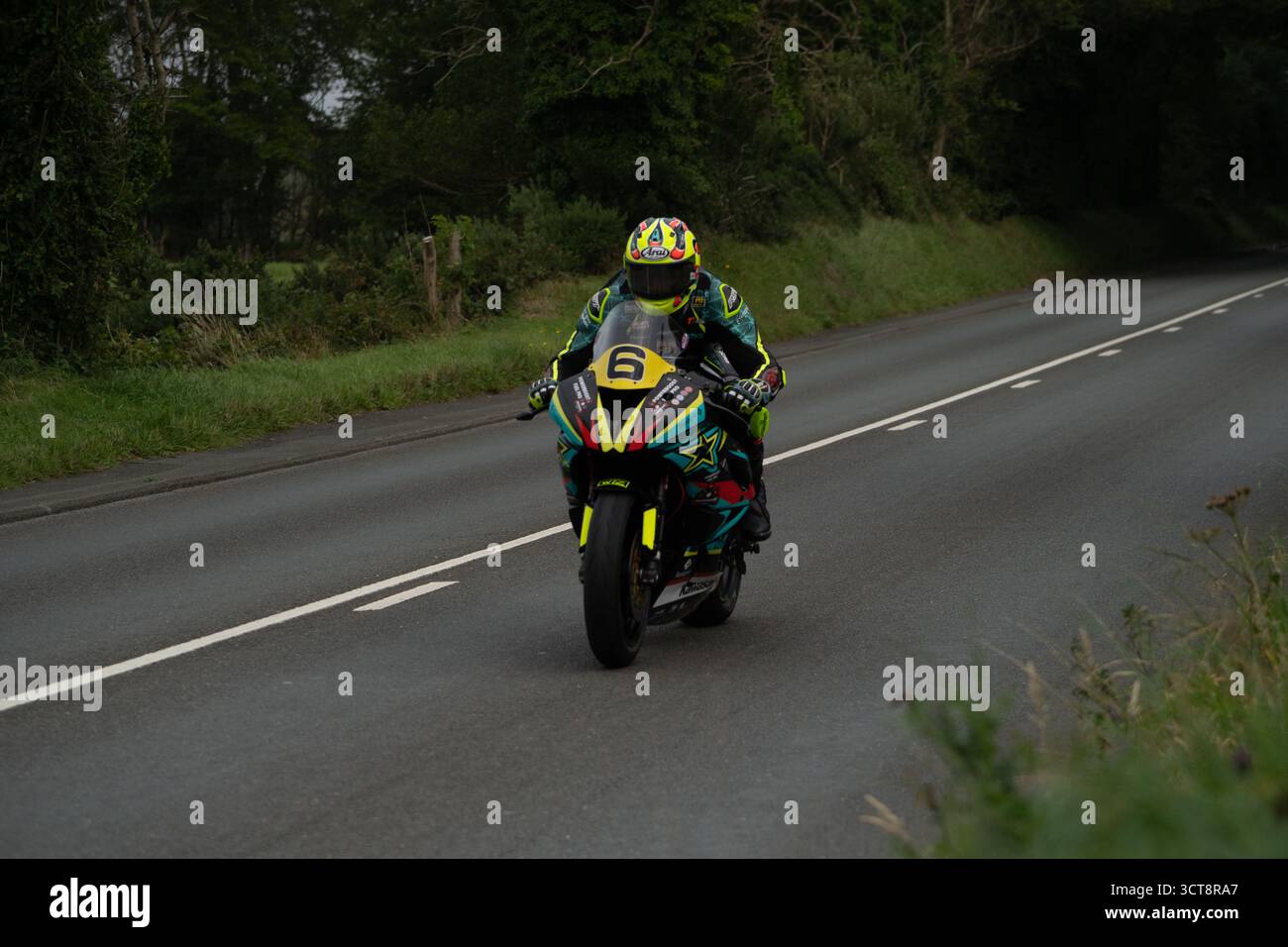 Moto da corsa numero 6 sulla strada rurale dell'Isola di Man circondata da verde campagna Foto Stock