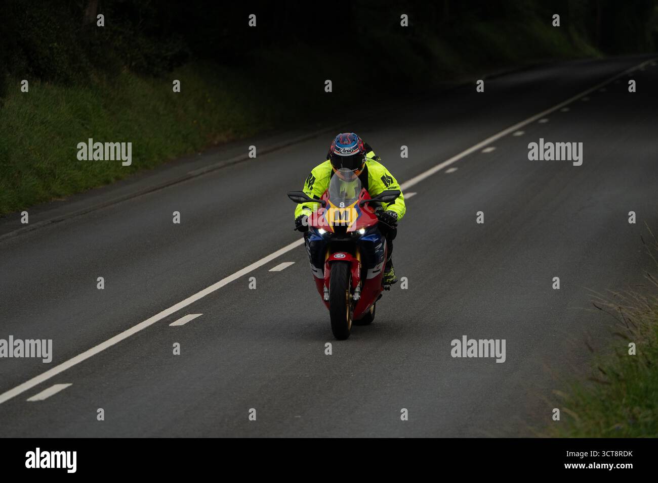 Motociclista in una gara di giacca ad alta visibilità sul percorso stradale dell'Isola di Man Foto Stock
