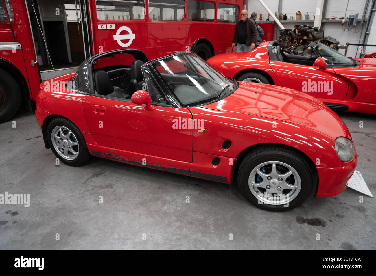 Auto sportiva rossa convertibile in esposizione al museo dei trasporti con autobus vintage a due piani Foto Stock