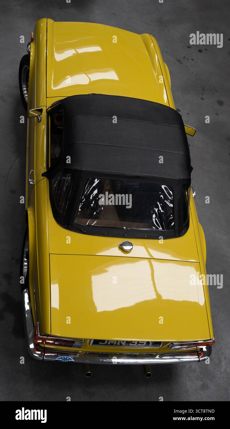 Vista aerea della classica auto sportiva gialla con tetto in tessuto nero su una superficie in cemento Foto Stock