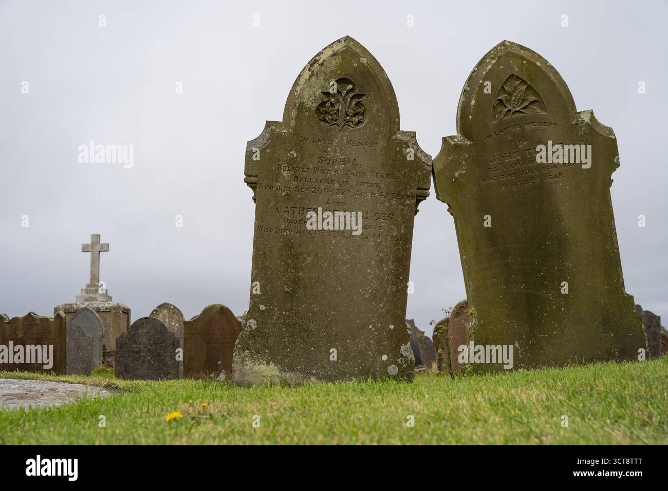 Storiche lapidi ricoperte di muschio nel cimitero dell'Isola di Man con dettagli decorativi scolpiti Foto Stock