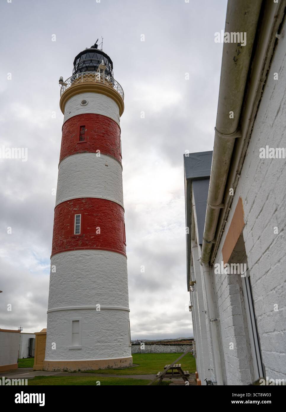 Faro a strisce rosse e bianche che torreggia contro il cielo nuvoloso sull'Isola di Man Foto Stock