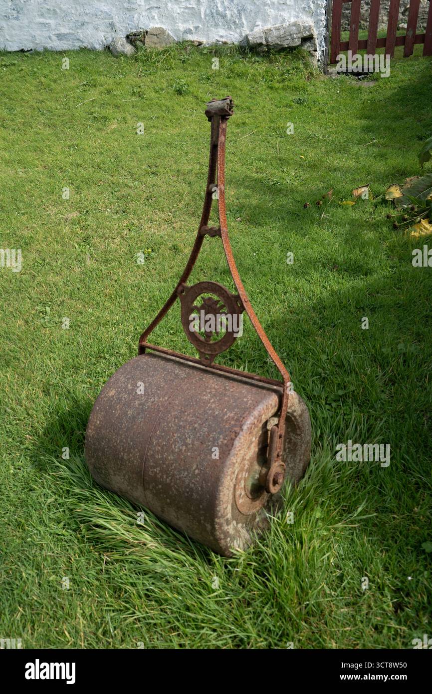 Rullo da prato in ghisa d'epoca su erba nel tradizionale giardino britannico Foto Stock