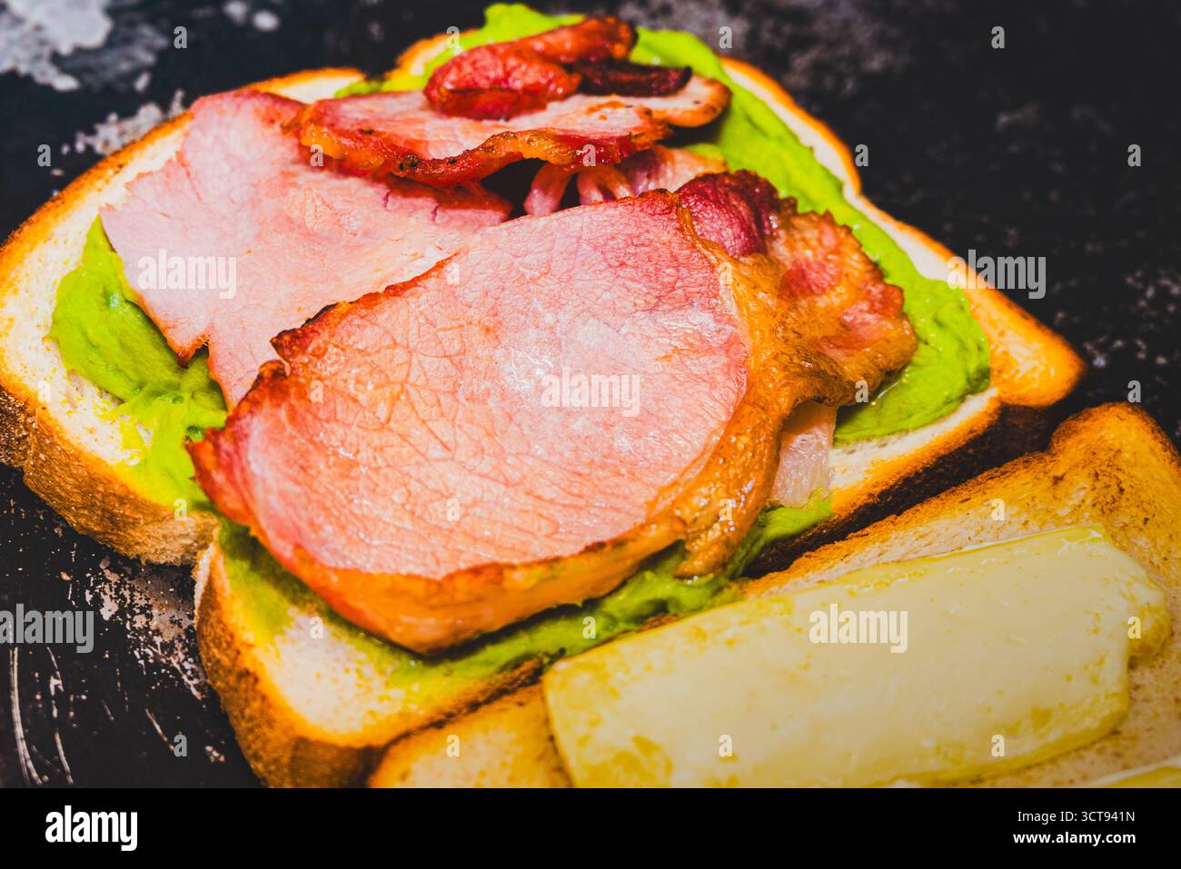 Toast all'avocado con pancetta e formaggio. Una gustosa colazione o un pranzo. Foto Stock