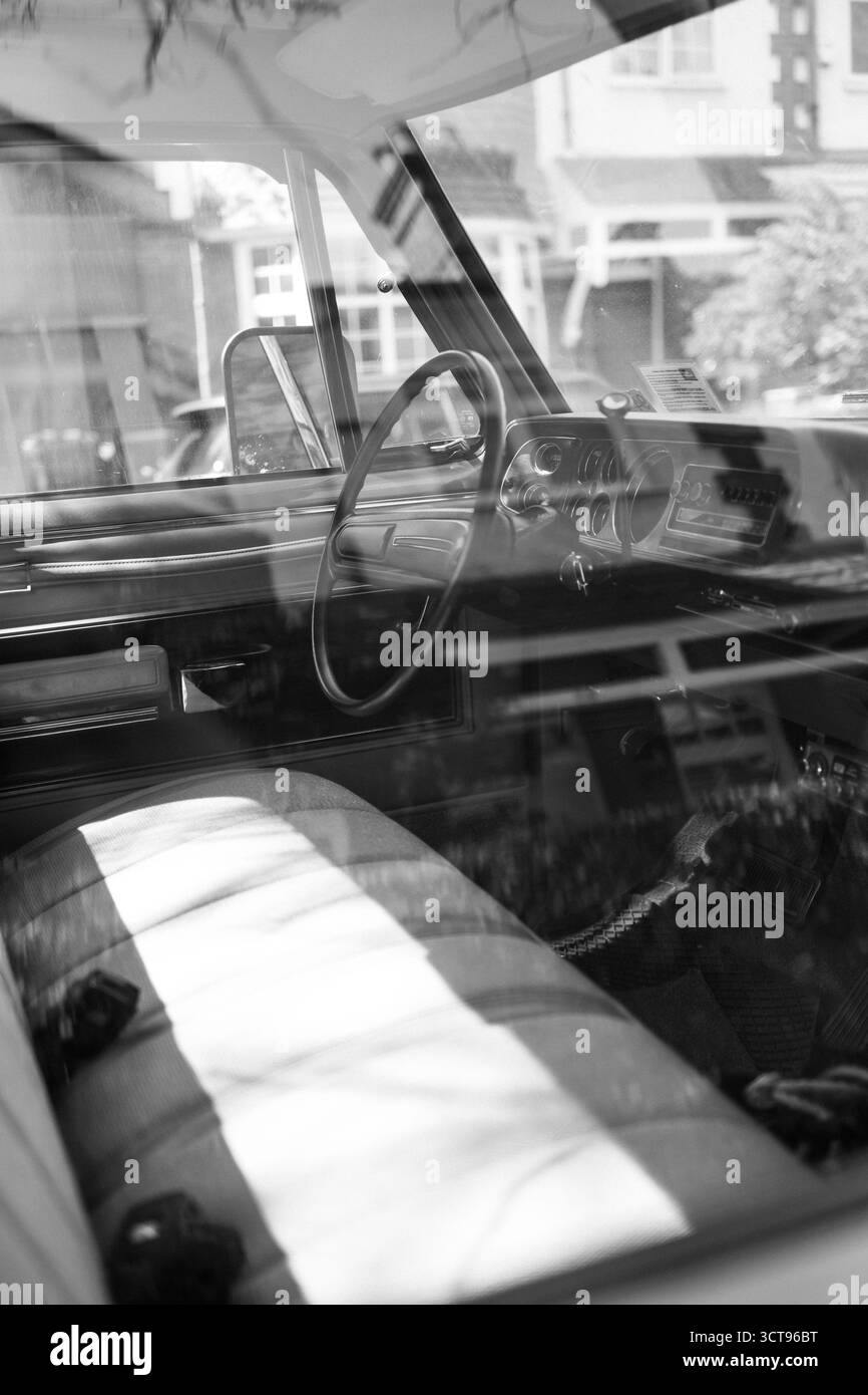 Chiswick, Londra – 2025.04.28 – foto in bianco e nero che cattura l'interno di un classico furgone Dodge attraverso la finestra, mostrando i riflessi del vicino Foto Stock