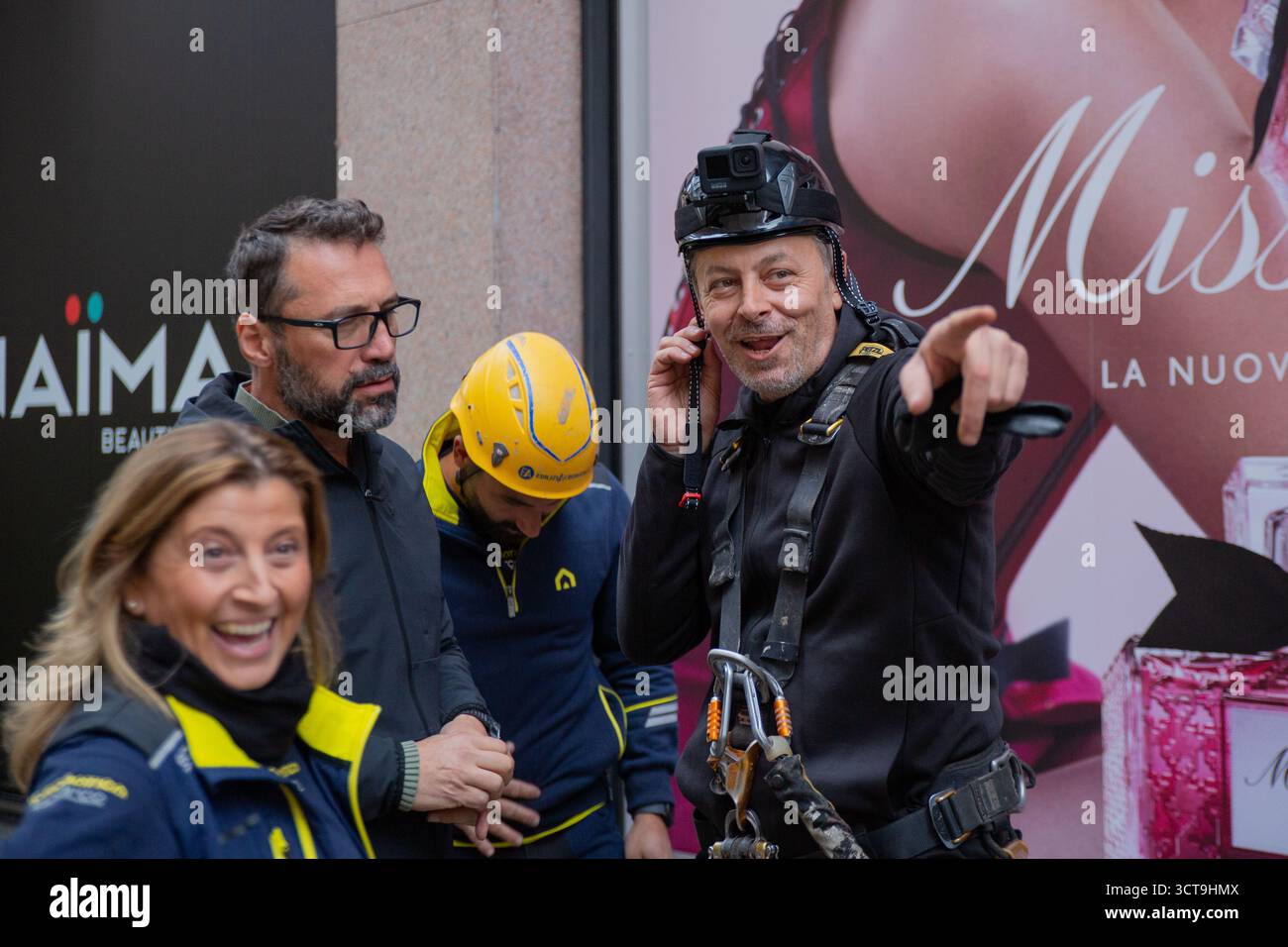 Un momento vivace durante la fase di preparazione cattura l'artista Enzo Mastrangelo sorridendo e facendo un gesto verso un individuo mentre è circondato da t Foto Stock