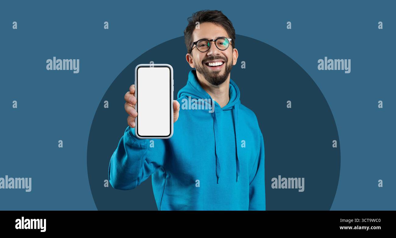 Collage creativo con un giovane che tiene in mano uno smartphone con schermo vuoto in un ambiente moderno Foto Stock