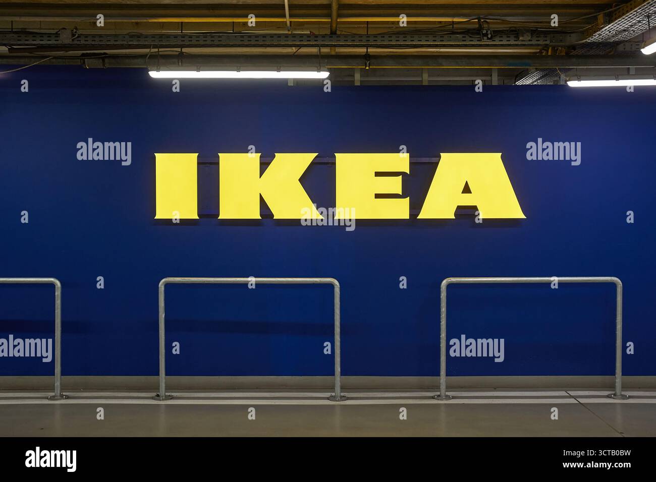 Cartello giallo del negozio Ikea sul muro blu nel parcheggio Foto Stock