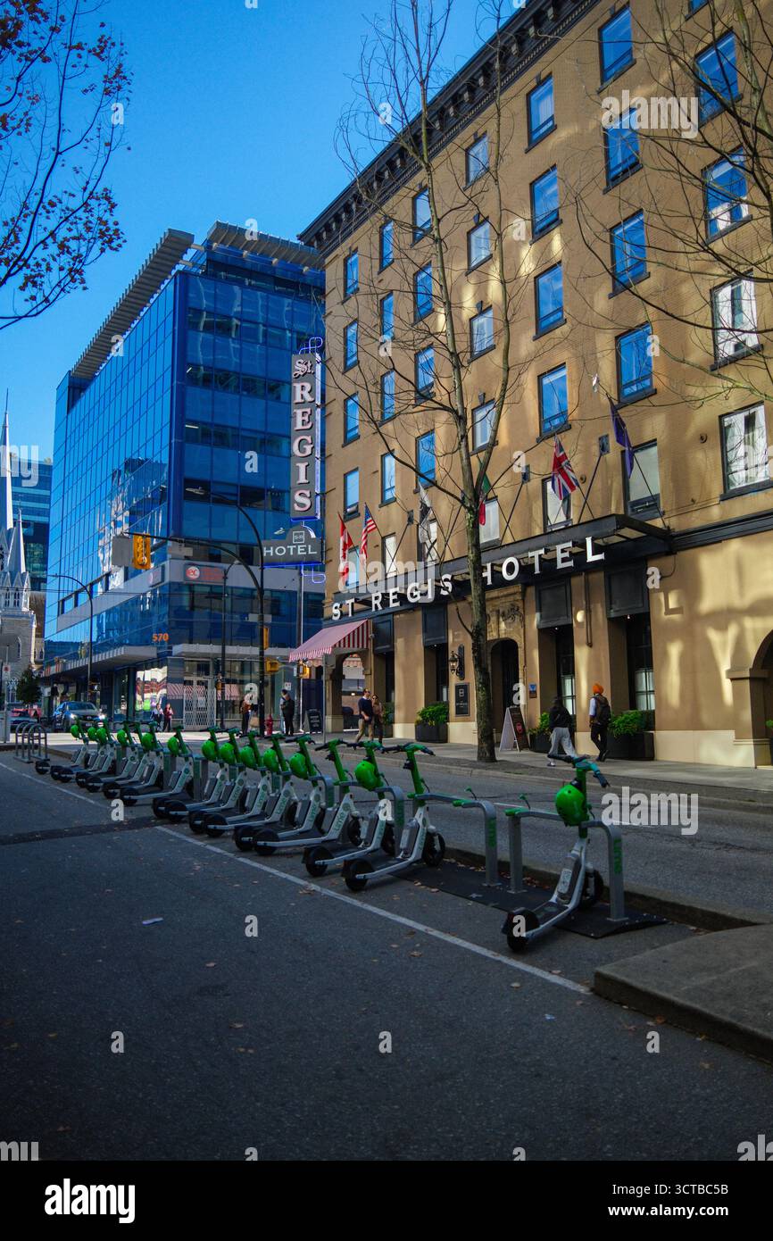 Una fila di e-scooter con il St Regis Hotel alle spalle lungo Dunsmuir Street nel centro di Vancouver, British Columbia. Foto Stock