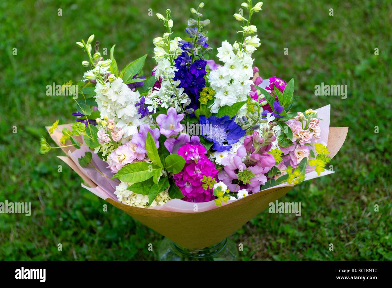 Bouquet di fiori avvolti di fiori primaverili misti. Splendidi fiori freschi rosa, bianco e blu. Bouquet di compleanno con larkspur e opaco Foto Stock