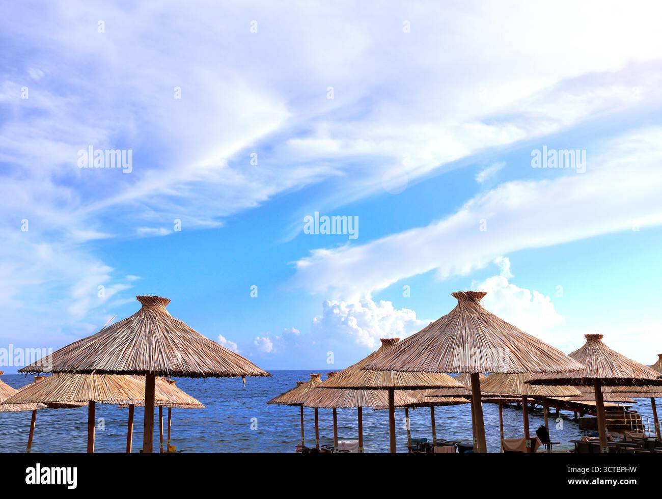 Ombrelloni da spiaggia fatti a mano da canne e mare Adriatico, Budva, Montenegro. Splendida scena con vista mare e ombrelloni realizzati con canne asciutte. Argomento o Foto Stock