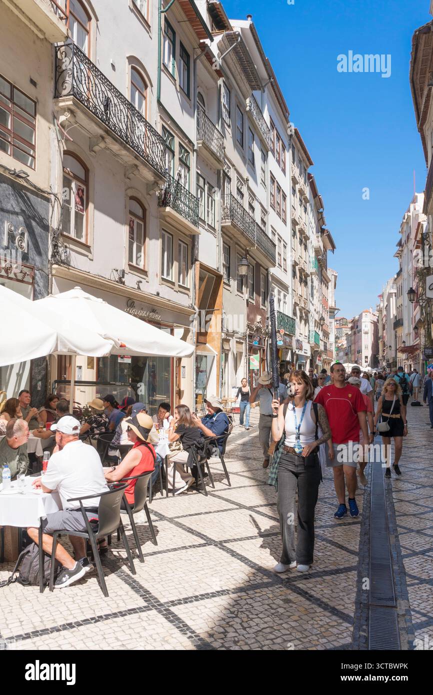 Guida turistica femminile che conduce un gruppo di visitatori attraverso una strada a Coimbra, Portogallo Foto Stock