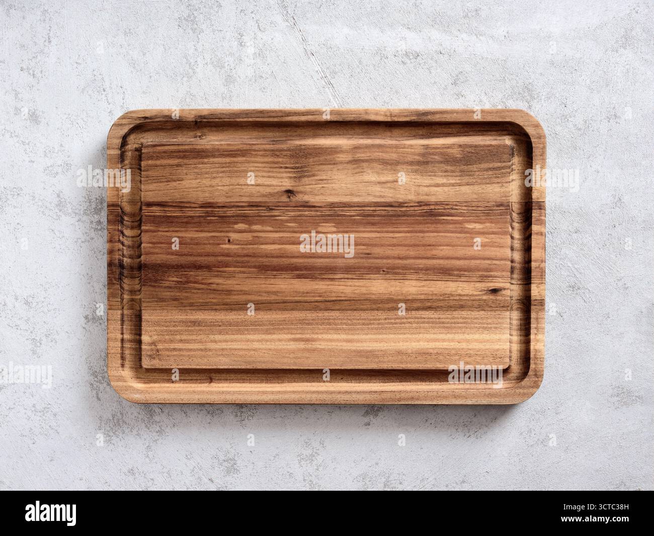 Lavare il tagliere in legno su una superficie ruvida grigia, fornendo una superficie rustica e naturale per la preparazione o la presentazione degli alimenti Foto Stock