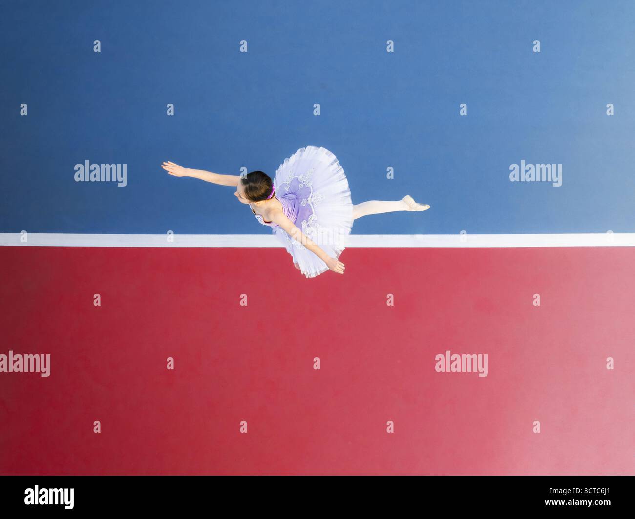 Veduta aerea di una ballerina in un tutù bianco che salta con grazia su uno sfondo vibrante di rosso e blu contrastanti, Adelaide, Australia meridionale, Australia. Foto Stock