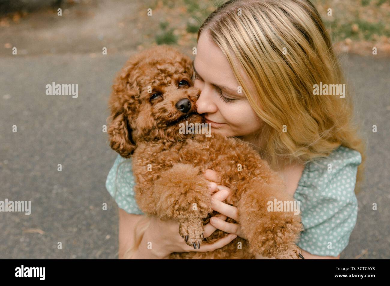 Donna che baciava il barboncino mentre teneva le braccia all'aperto Foto Stock