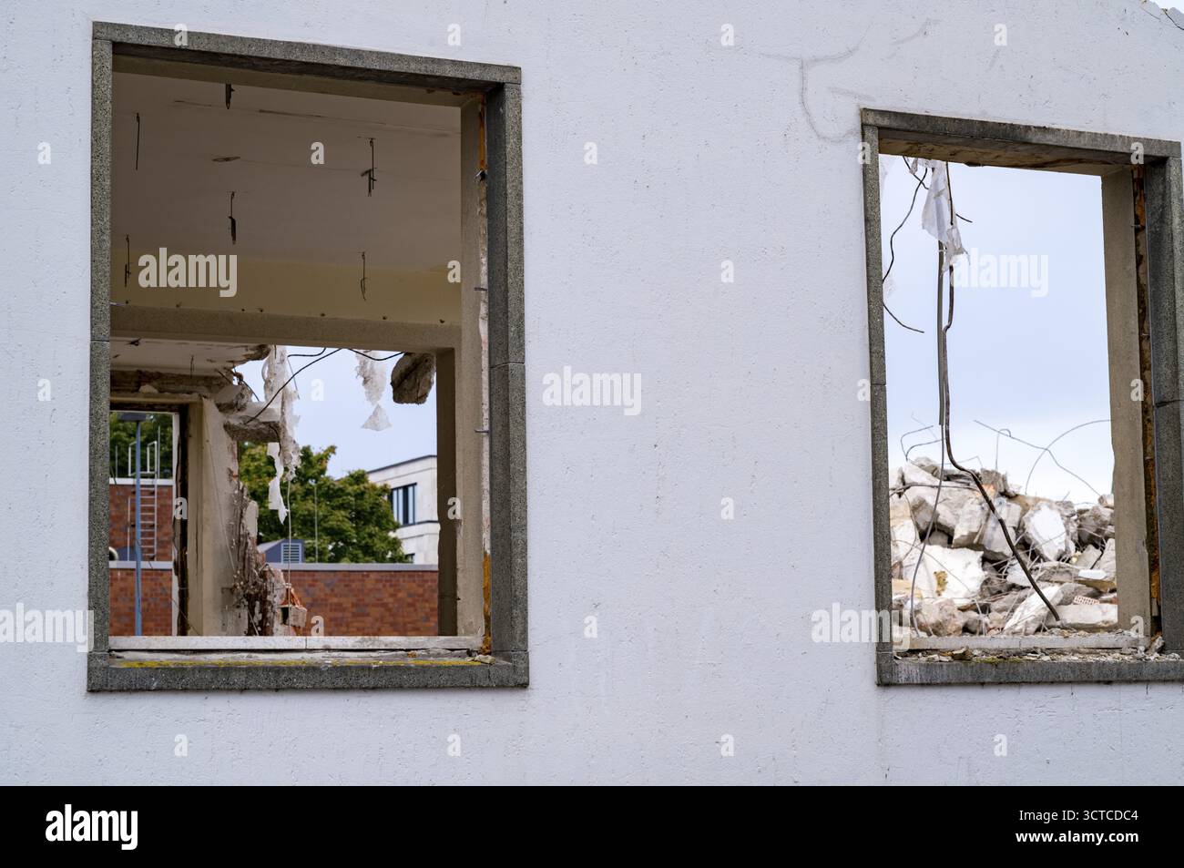Edificio demolito che mostra rovine di cemento e tondini intrecciati attraverso telai vuoti delle finestre Foto Stock