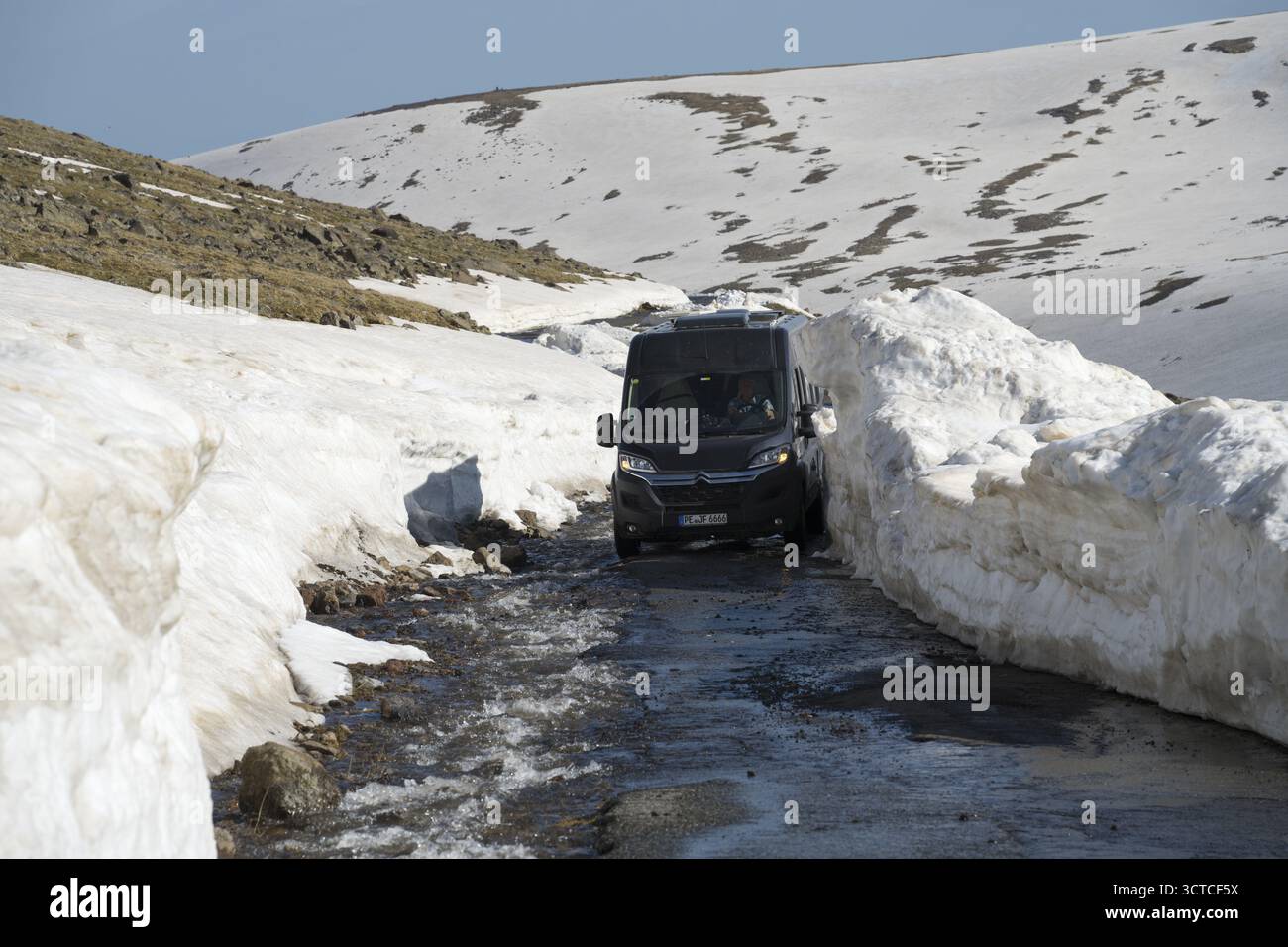 Van navigiert durch schmale, schneebedeckte Bergstrasse bei Sonnenlicht, mit dem camper zum Aragaz, Aragats, Aragac, Alagyaz, erloschener Schichtvulka Foto Stock