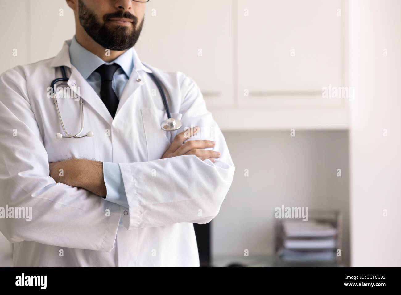 Primo piano di terapeuta maschile sicuro in piedi con le braccia incrociate Foto Stock