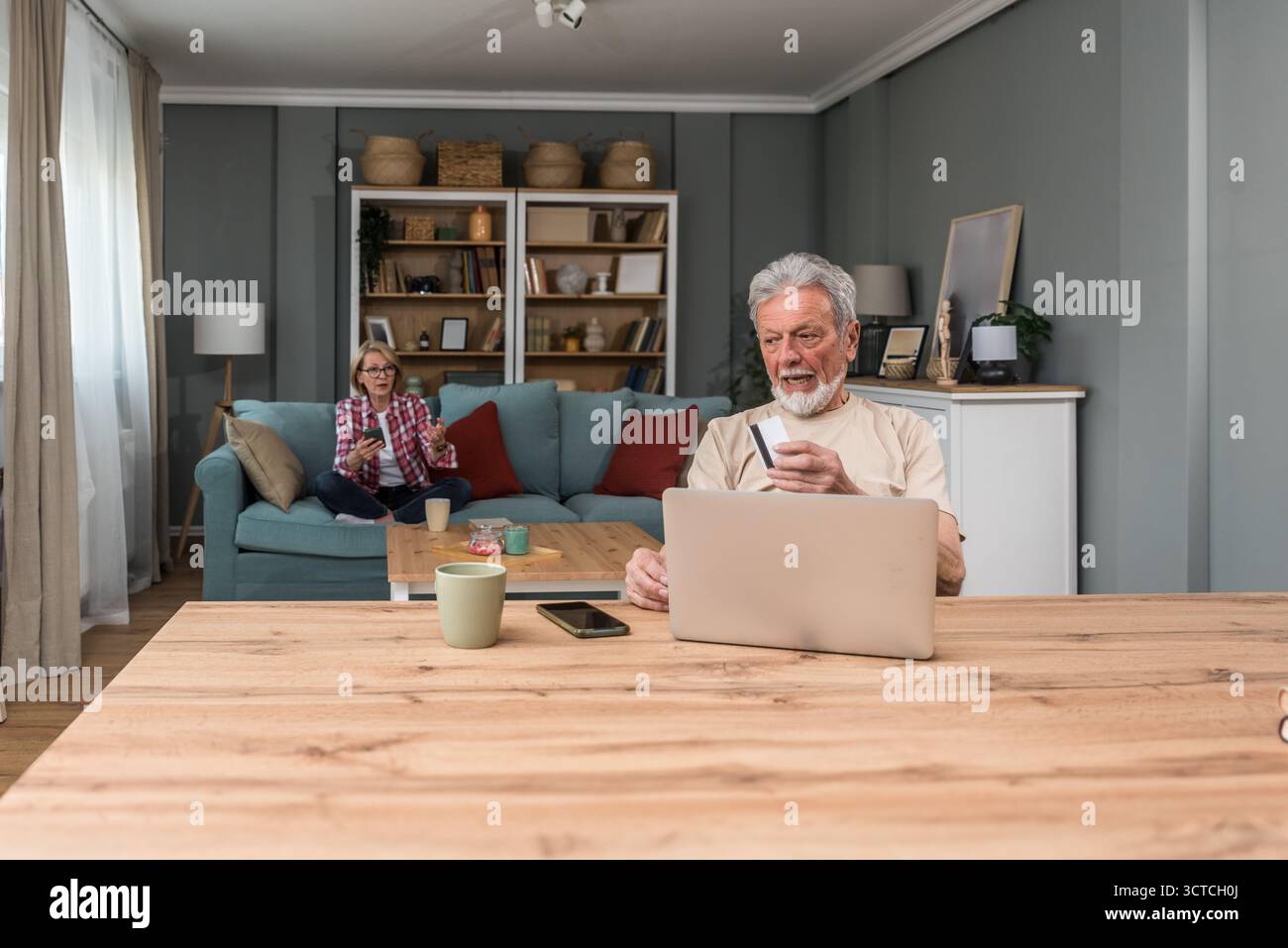 Coppia di anziani, persone anziane vivono in modo semplice, seduti a casa, utilizzano la tecnologia per la prima volta, ordinano e fanno acquisti online su un computer portatile da loro Foto Stock