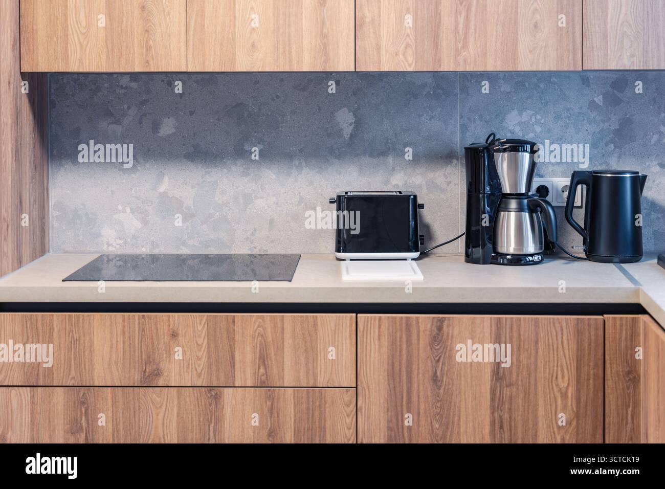 Un moderno interno della cucina con armadi in legno, spruzzi di pietra e piccoli elettrodomestici come un tostapane e una macchina per il caffè Foto Stock