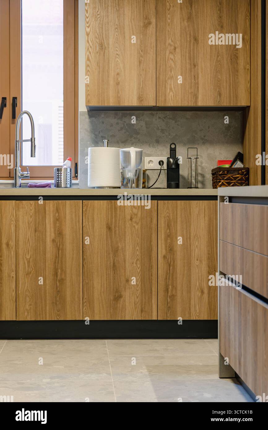 Un moderno interno della cucina con armadi in legno, spruzzi di pietra e piccoli elettrodomestici come un tostapane e una macchina per il caffè Foto Stock