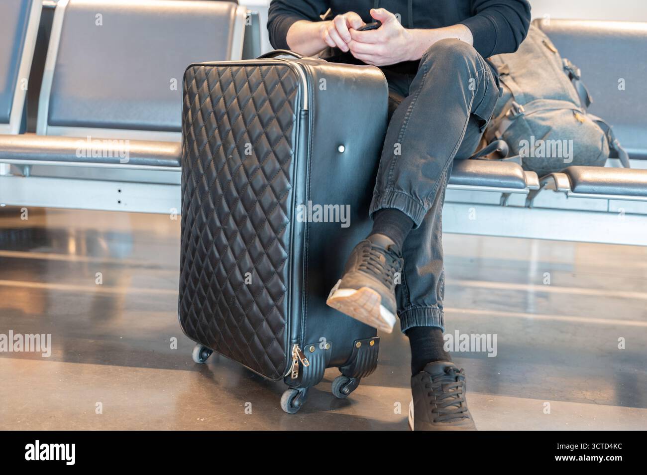 Un viaggiatore elegante vi aspetta all'aeroporto con il loro bagaglio alla moda e accattivante Foto Stock