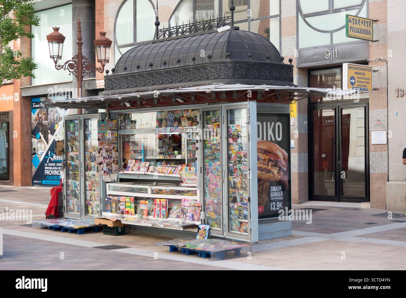 Moderno chiosco di giornali che unisce design classico e porte in vetro in un ambiente urbano, combinando fascino tradizionale con funzionalità contemporanee. Foto Stock