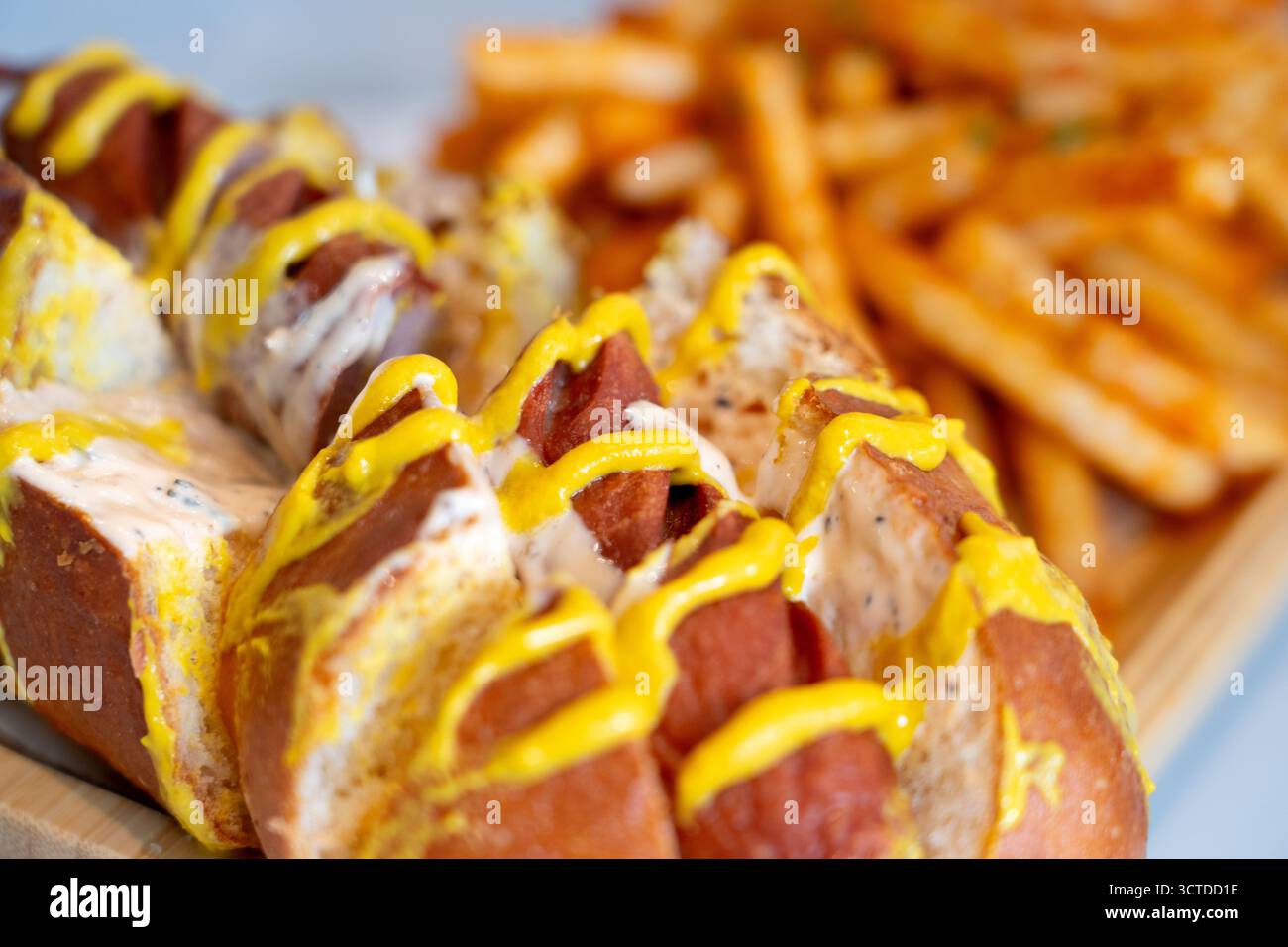Hot dog caricati in soffici panini di pretzel con condimenti vivaci, serviti insieme a patatine fritte dorate per un pasto perfetto e appagante. Foto Stock