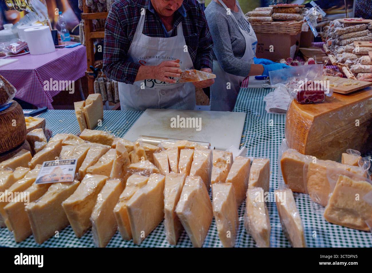 diverse varietà di formaggio agricolo si trovano sul bancone pronto per la vendita. mani di una persona non identificabile che taglia il formaggio a pezzi Foto Stock