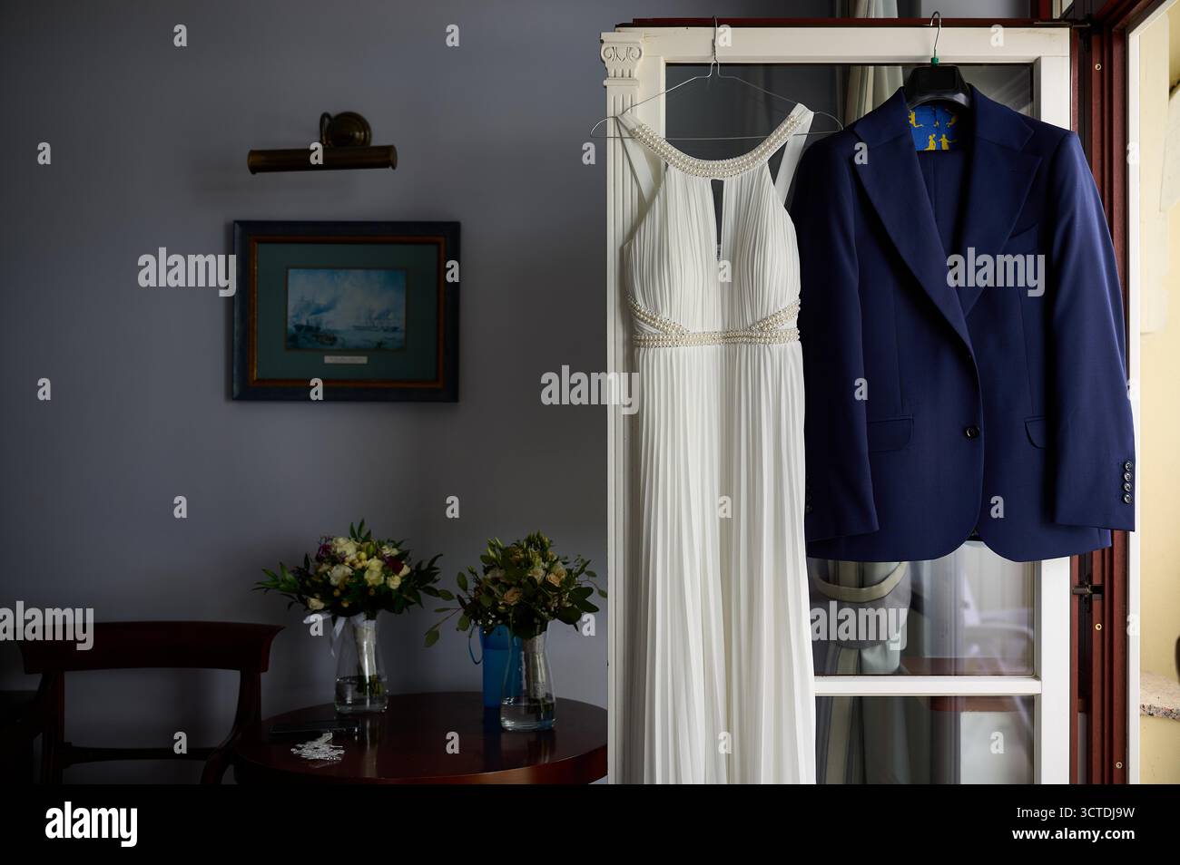Camera da letto interna con tute formali appese in preparazione di matrimoni o eventi formali Foto Stock