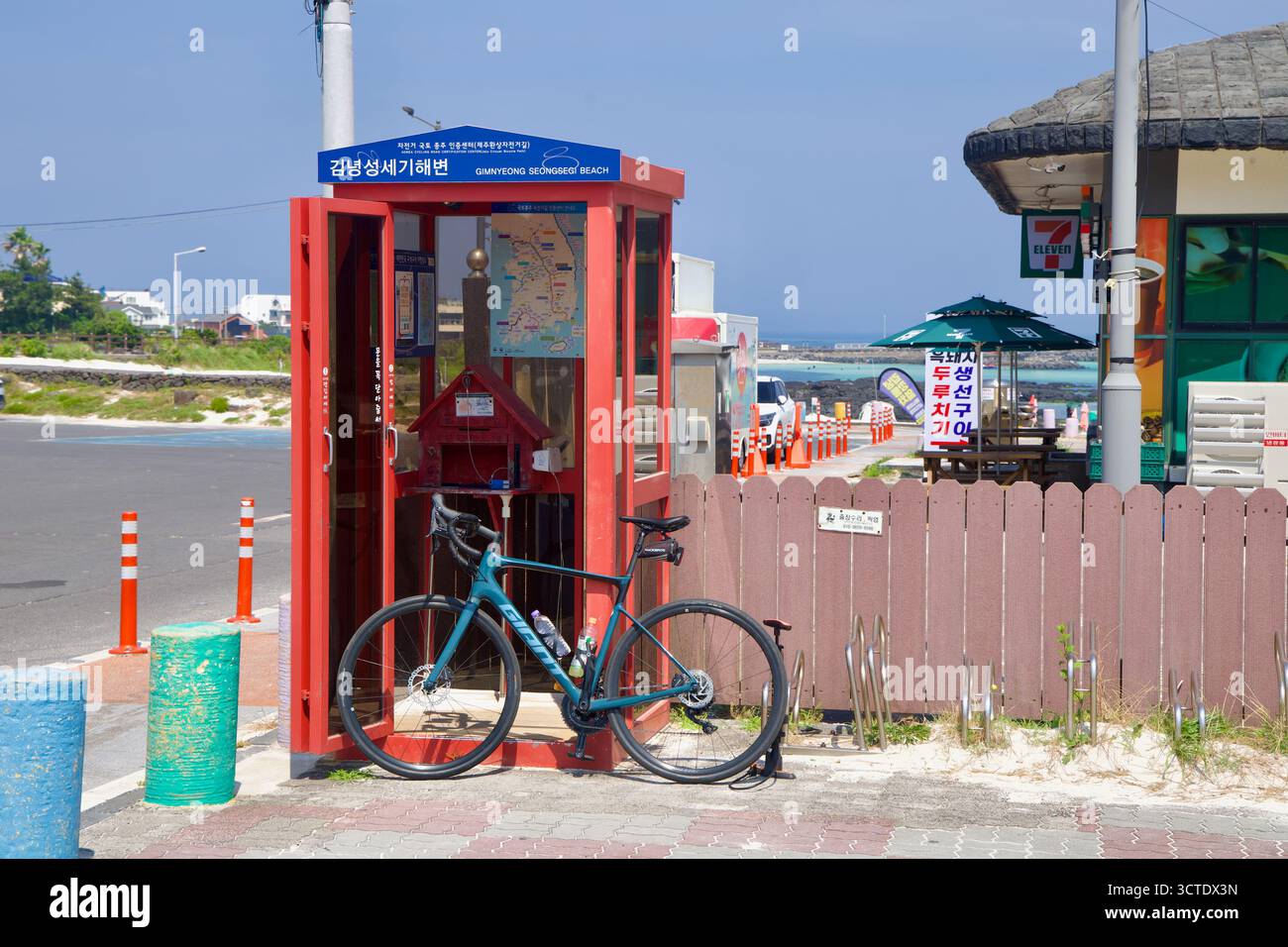 Una bicicletta da strada si appoggia allo stand rosso del Gimnyeong Seongsegi Beach Certification Center, un posto di blocco utilizzato dai ciclisti sulla rotta costiera di Jeju Foto Stock