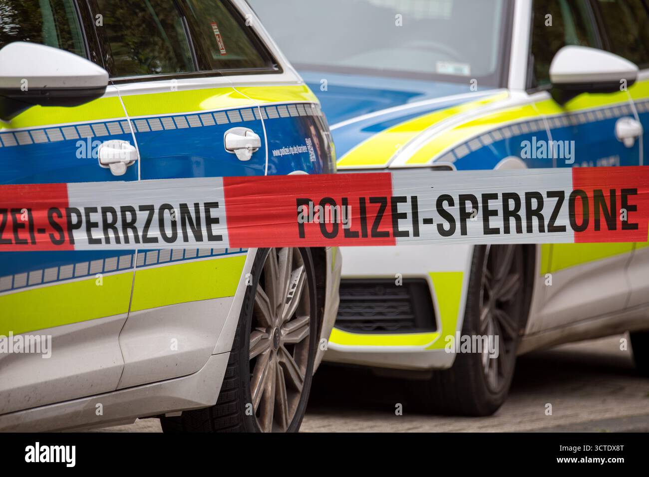 (Fotomontaggio) immagine simbolica dell'operazione di polizia: Nastro barriera di polizia davanti ai veicoli di emergenza Foto Stock (Fotomontaggio) immagine simbolica dell'operazione di polizia: Nastro barriera di polizia davanti ai veicoli di emergenza Foto Stock
