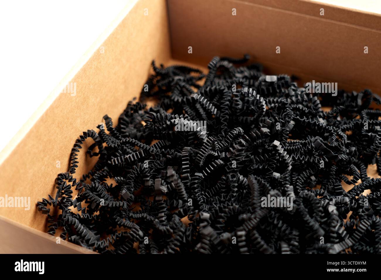 Aprire la scatola di cartone con carta grattugiata nera. Concetto di imballaggio di articoli fragili Foto Stock